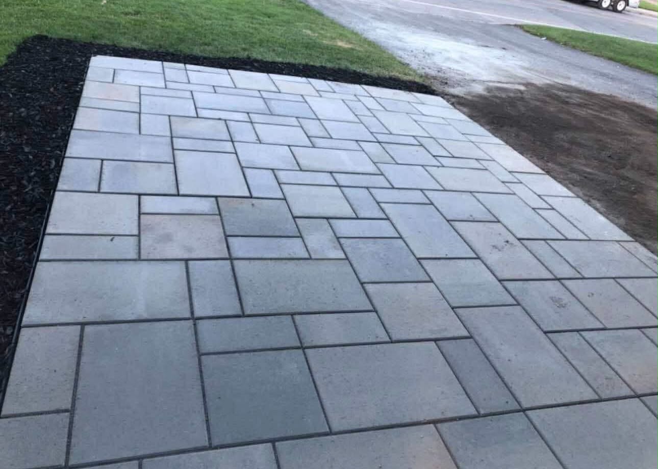 Random-pattern grey paver apron meeting the road, edged with black mulch