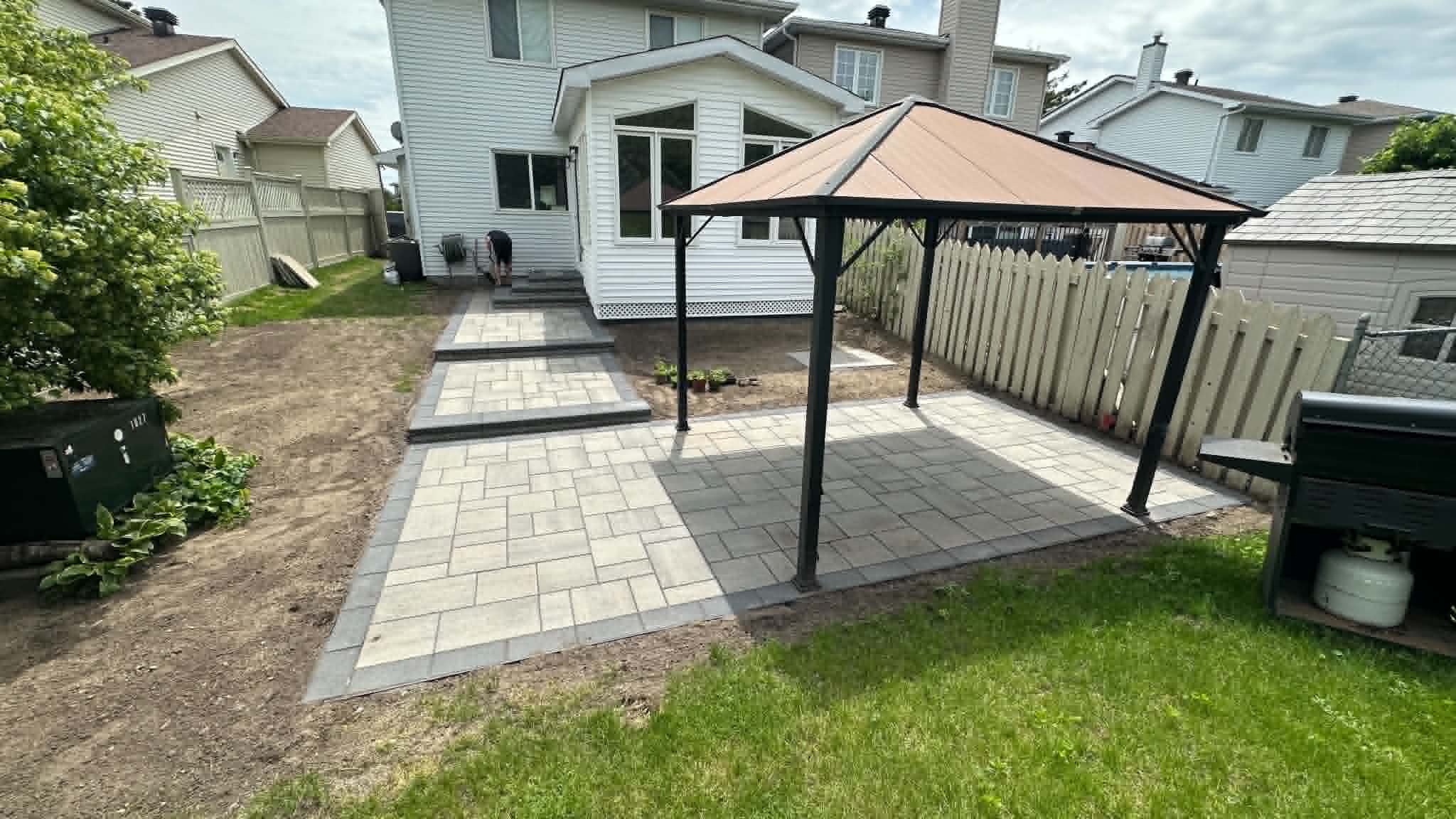 Two-tone backyard patio with a hard-top gazebo and a paver walkway to the rear steps