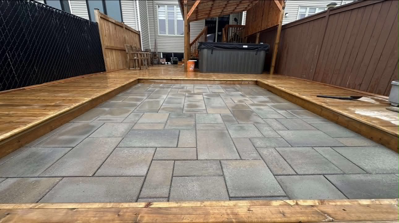 Grey slab patio set into a cedar deck with a hot tub under a timber pergola