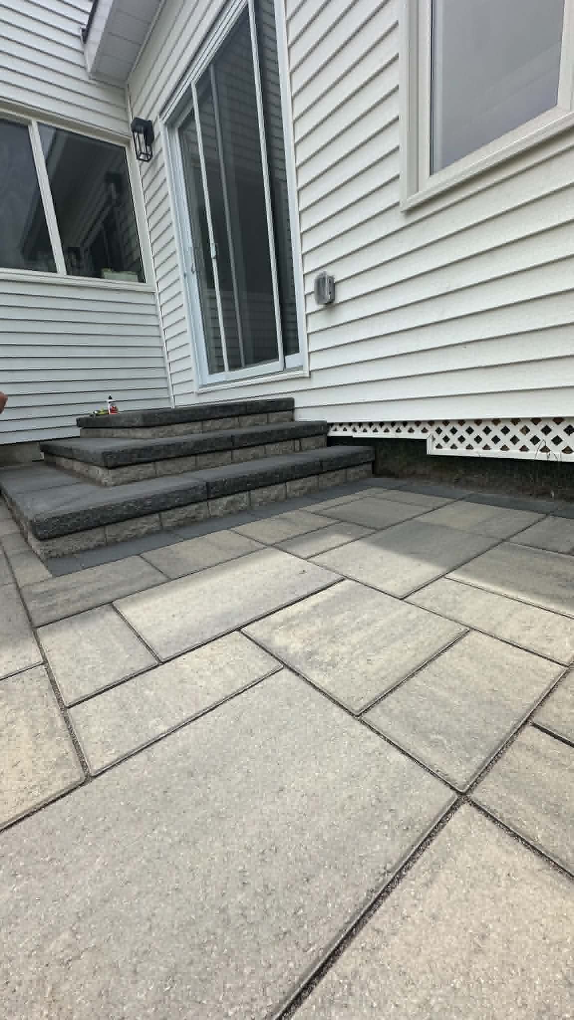 Beige slab patio with charcoal-capped block steps at a sliding patio door