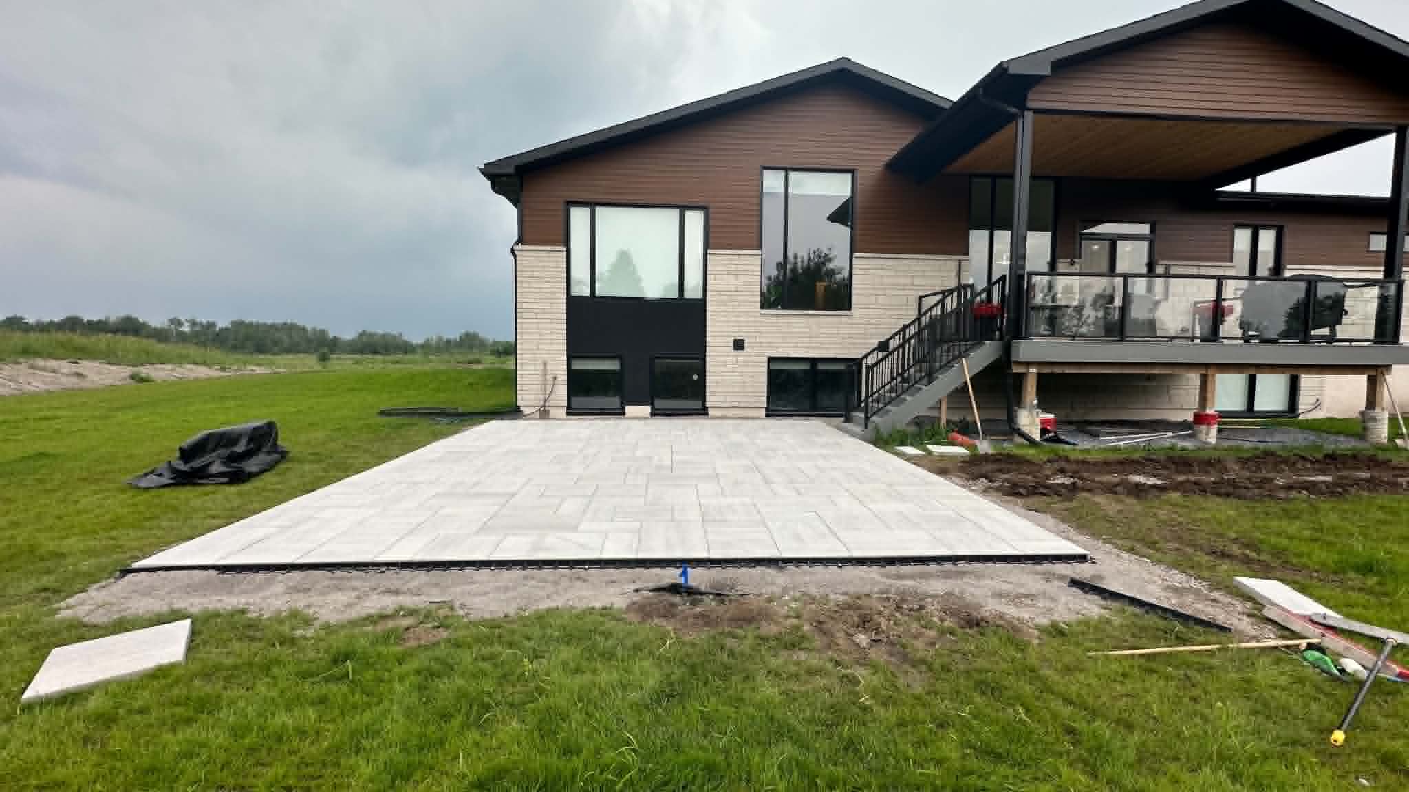 White slab patio laid out from the walkout basement of a modern rural home