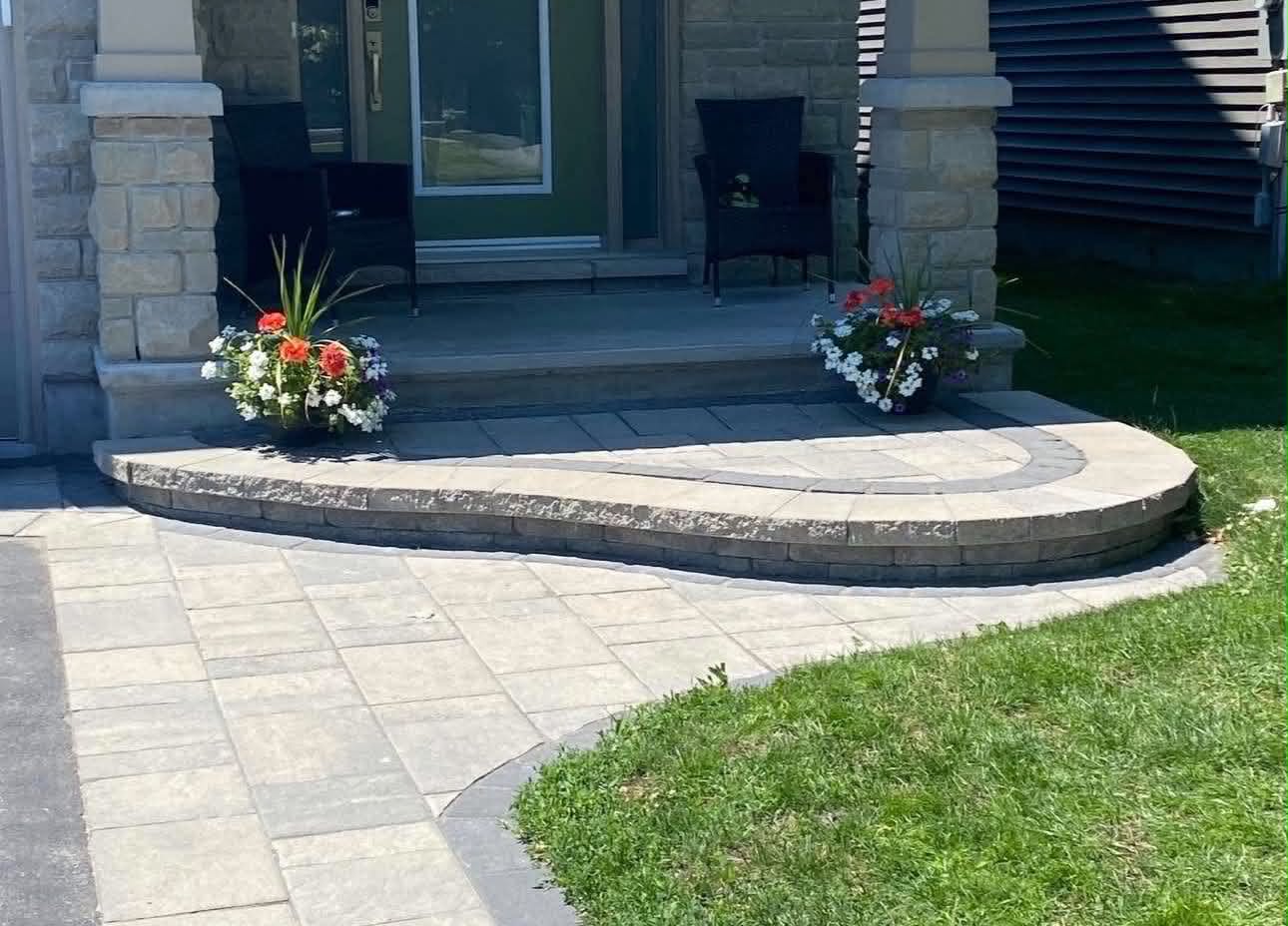 Curved paver seating wall and walkway sweeping up to a front entrance with planters