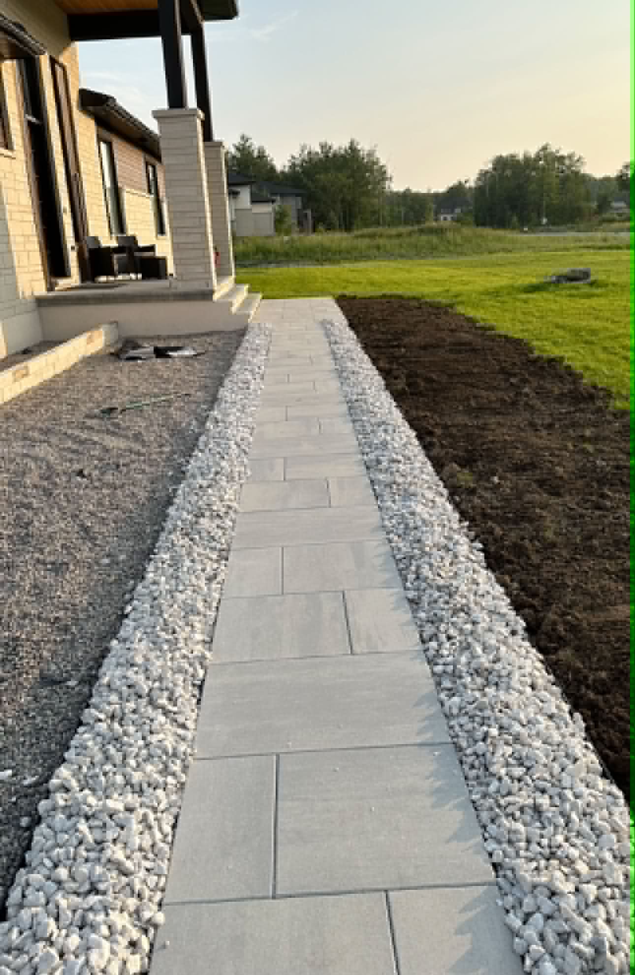 Side walkway leading past a stone-faced raised landing with a black glass railing