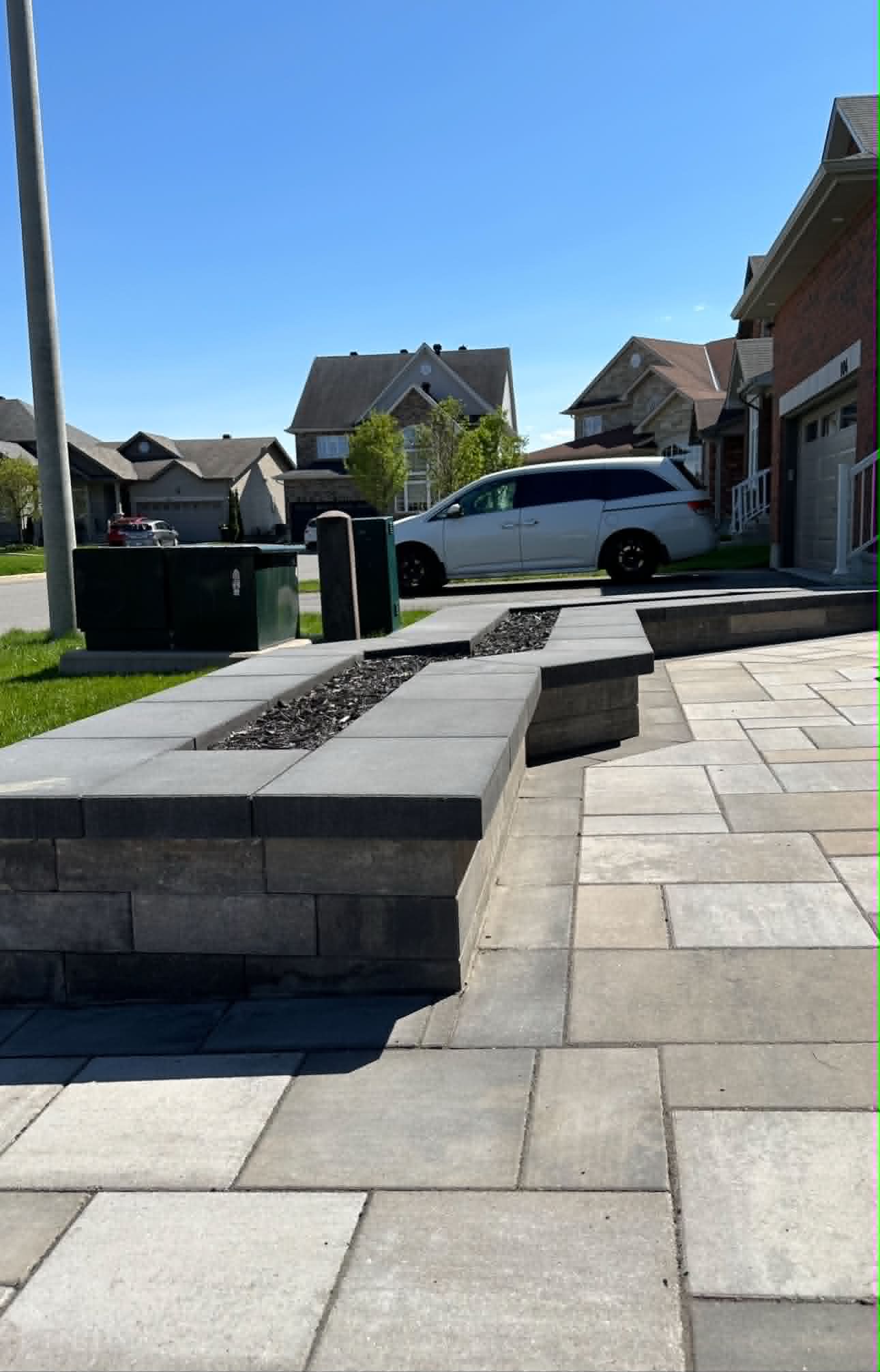 Wide front walkway with a low charcoal-capped planter wall running out to the street