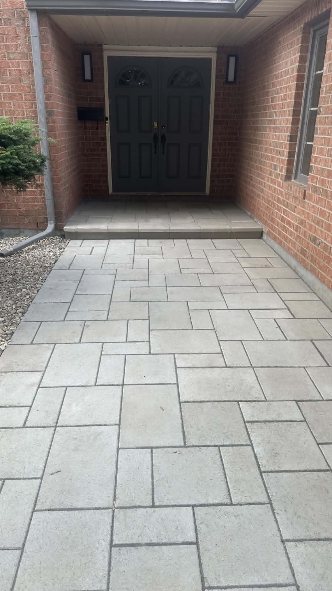 Large-format paver landing and step at a recessed brick front entrance with double doors