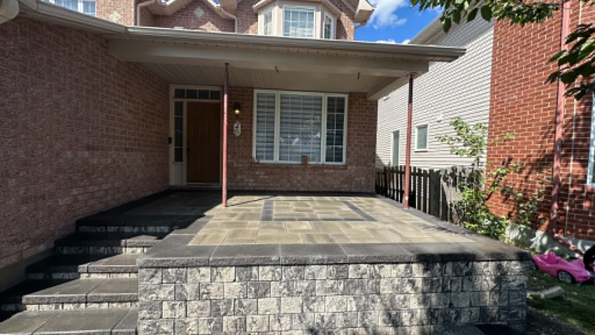 Raised paver front porch and entrance steps faced with a stacked-stone wall