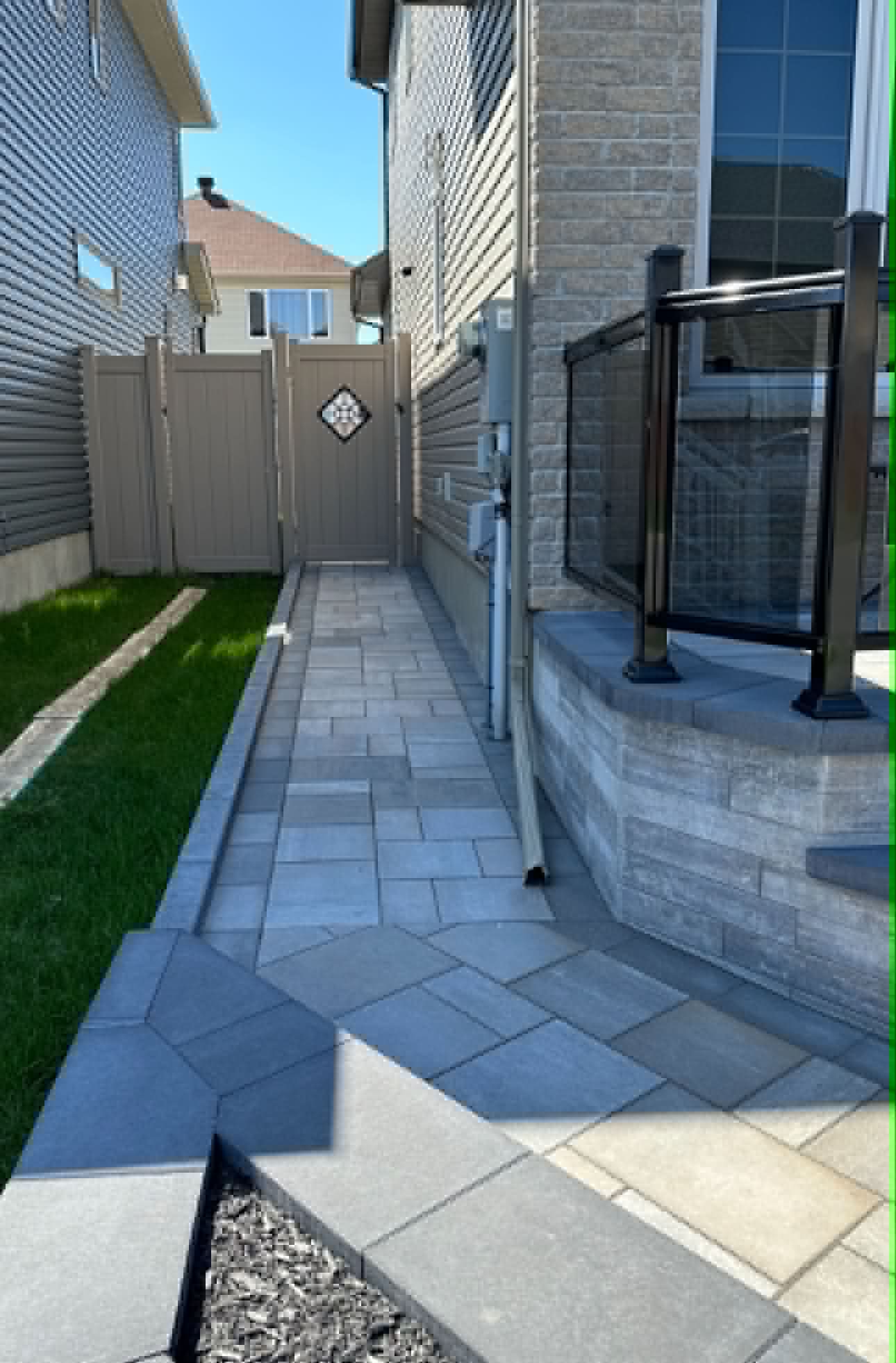 Straight slab walkway edged in white decorative stone running along a new build at sunset