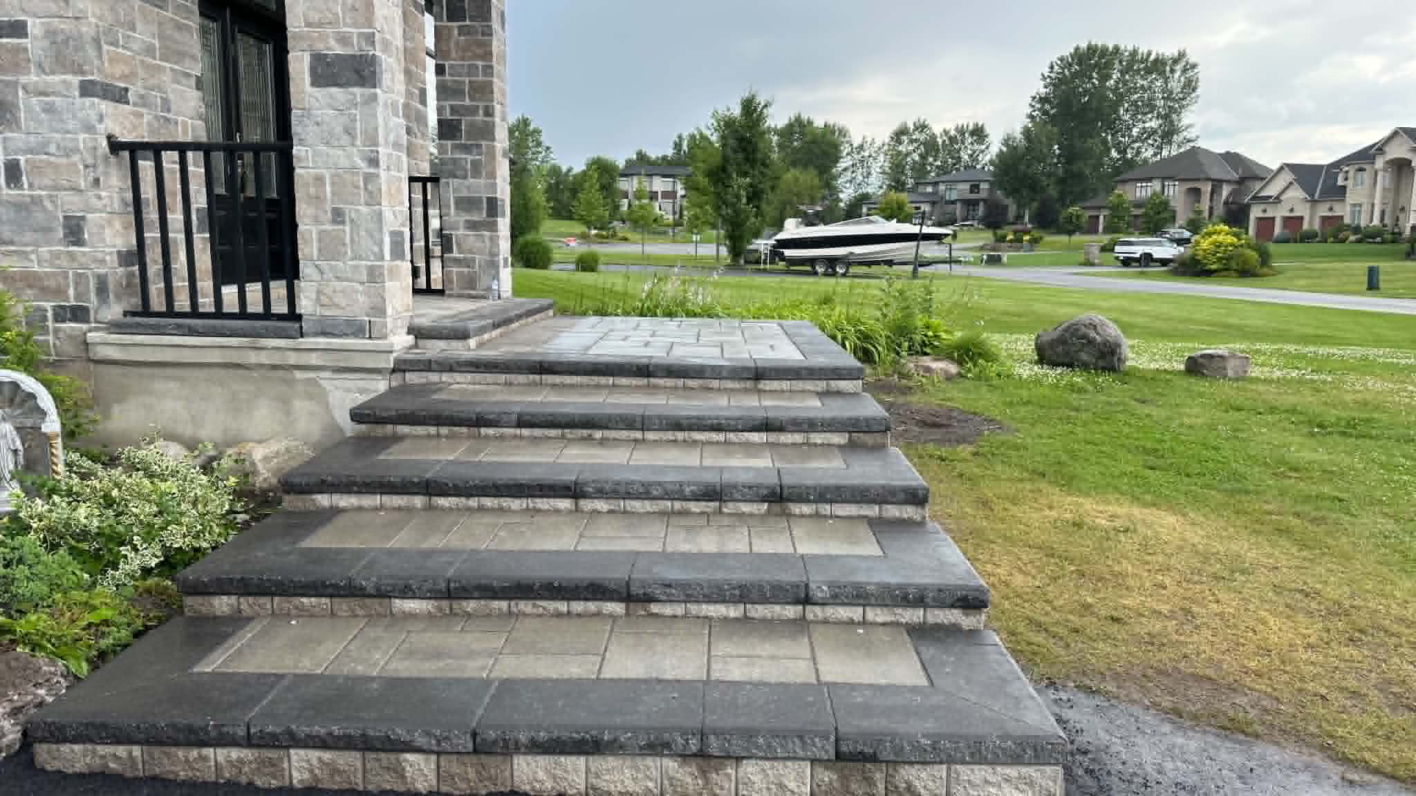 Wide paver front steps with charcoal treads and beige inlays at a stone-faced estate home