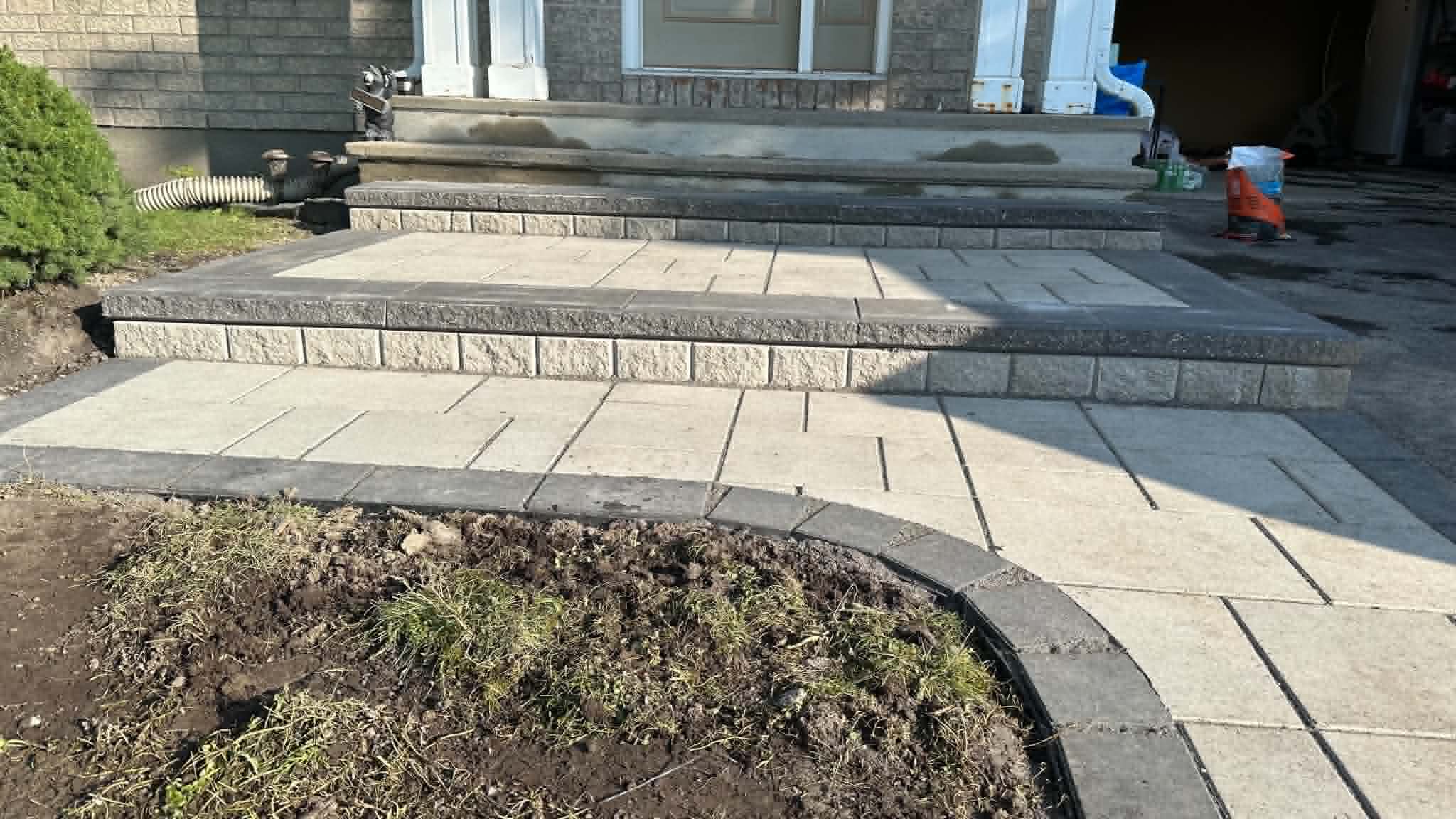 Beige paver landing and steps with charcoal caps and borders wrapping a front porch