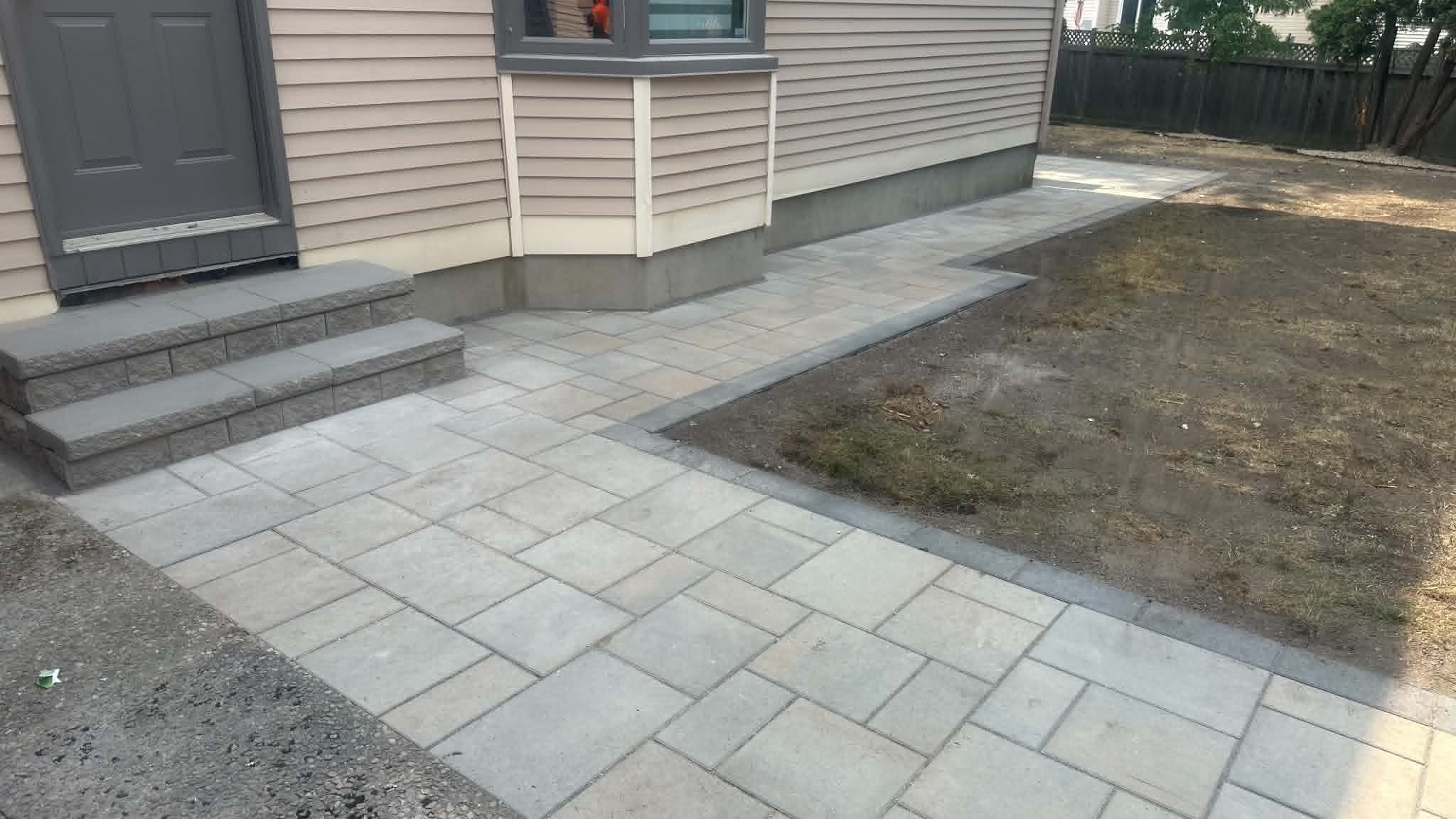 Grey slab front walk and block steps with a charcoal border at the front door
